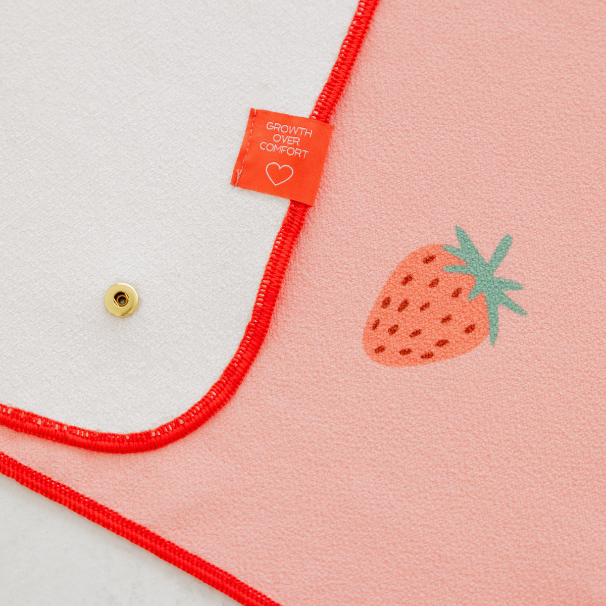 pink yoga mat towel with strawberry print and "growth over comfort" tag