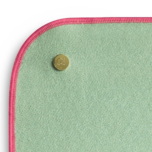 Green fabric with pink trim and a gold button on a white background