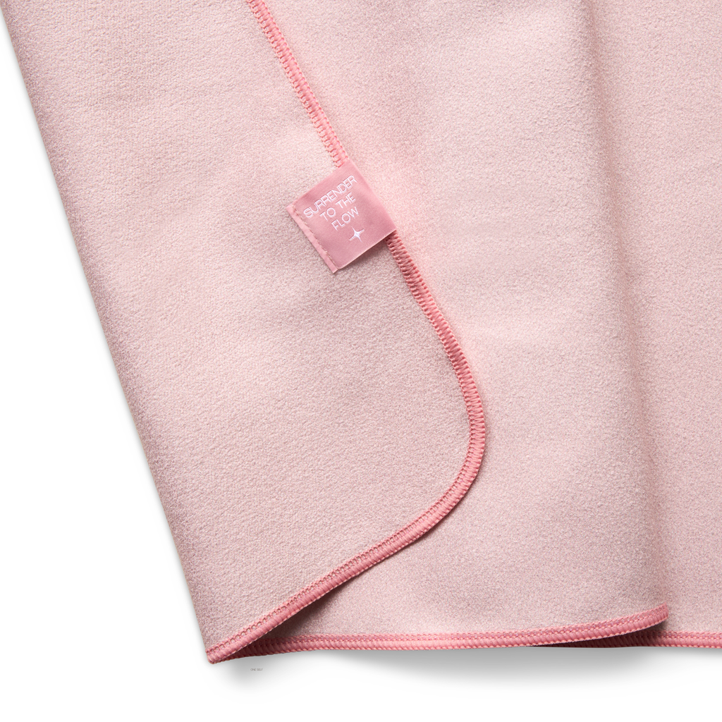Pink hand towel folded with a brand label on a white background