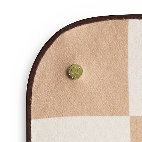 Round mat towel corner with checkered pattern and gold button on a white background