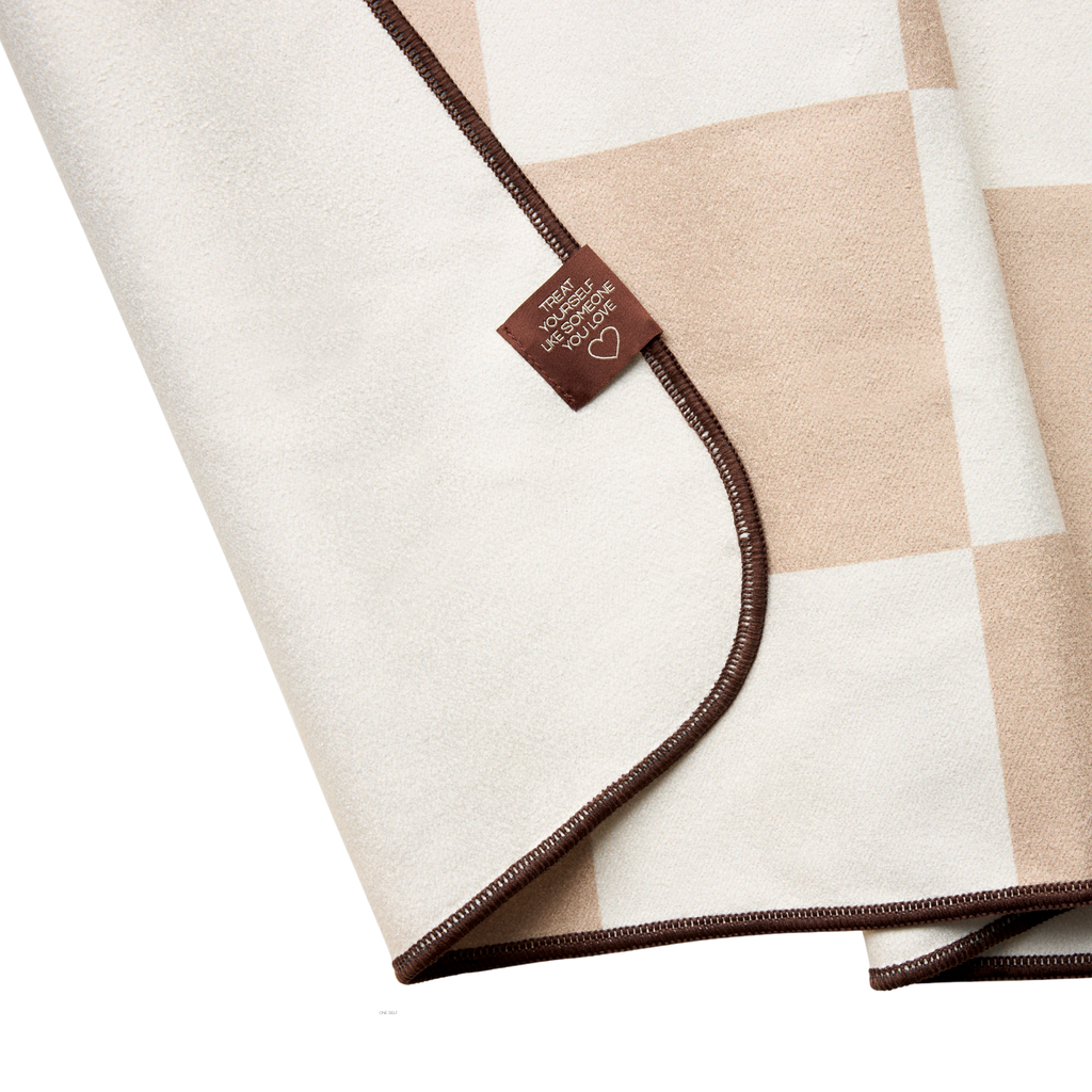 Folded checkered hand towel with a brown border and a tag on a white background