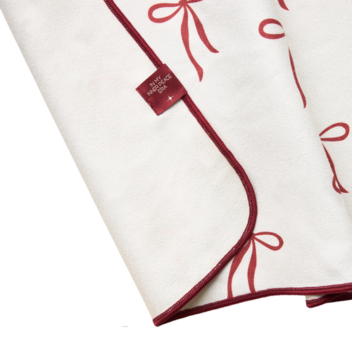 White and red hand towel folded with red ribbons and a brand label on a white background