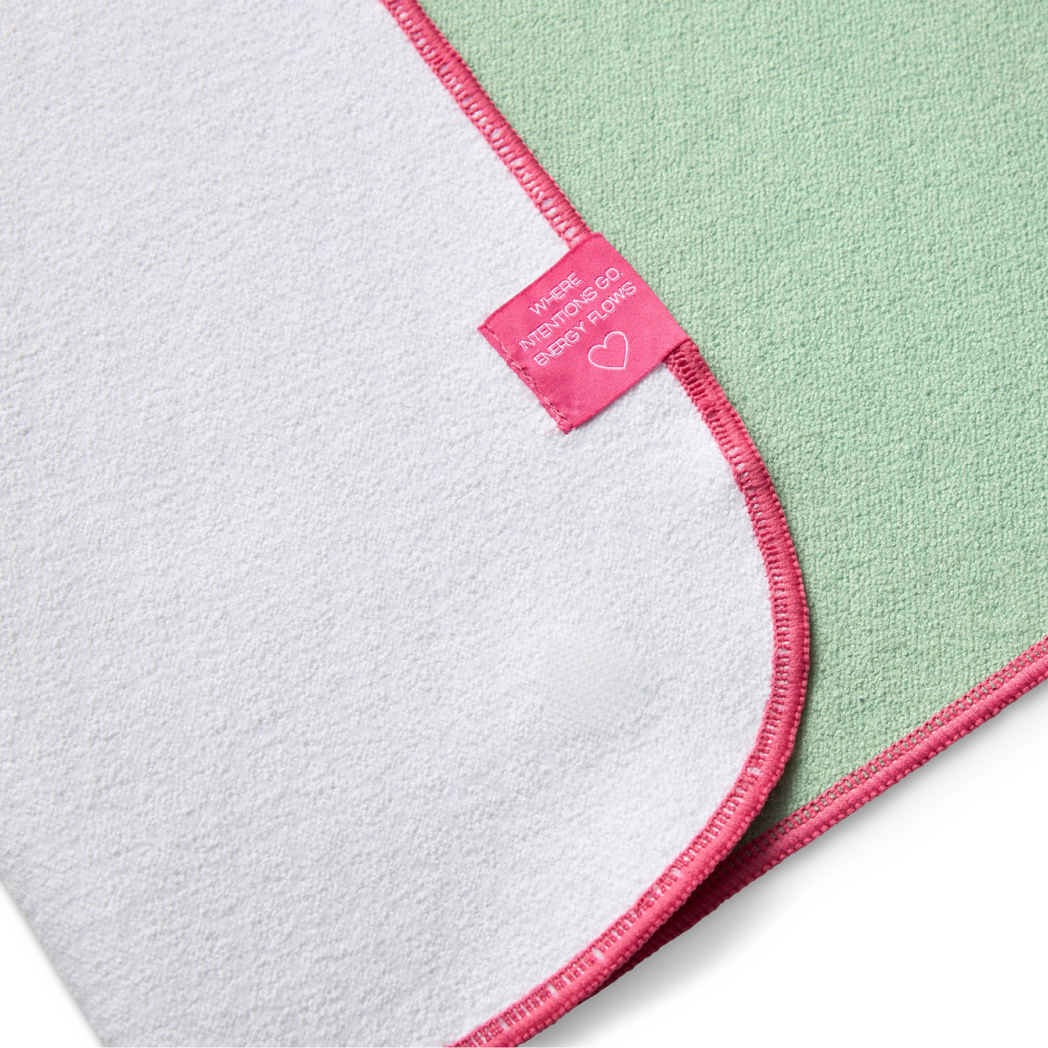 green yoga mat towel folded to show white background and tag that says "where intentions go energy flows"