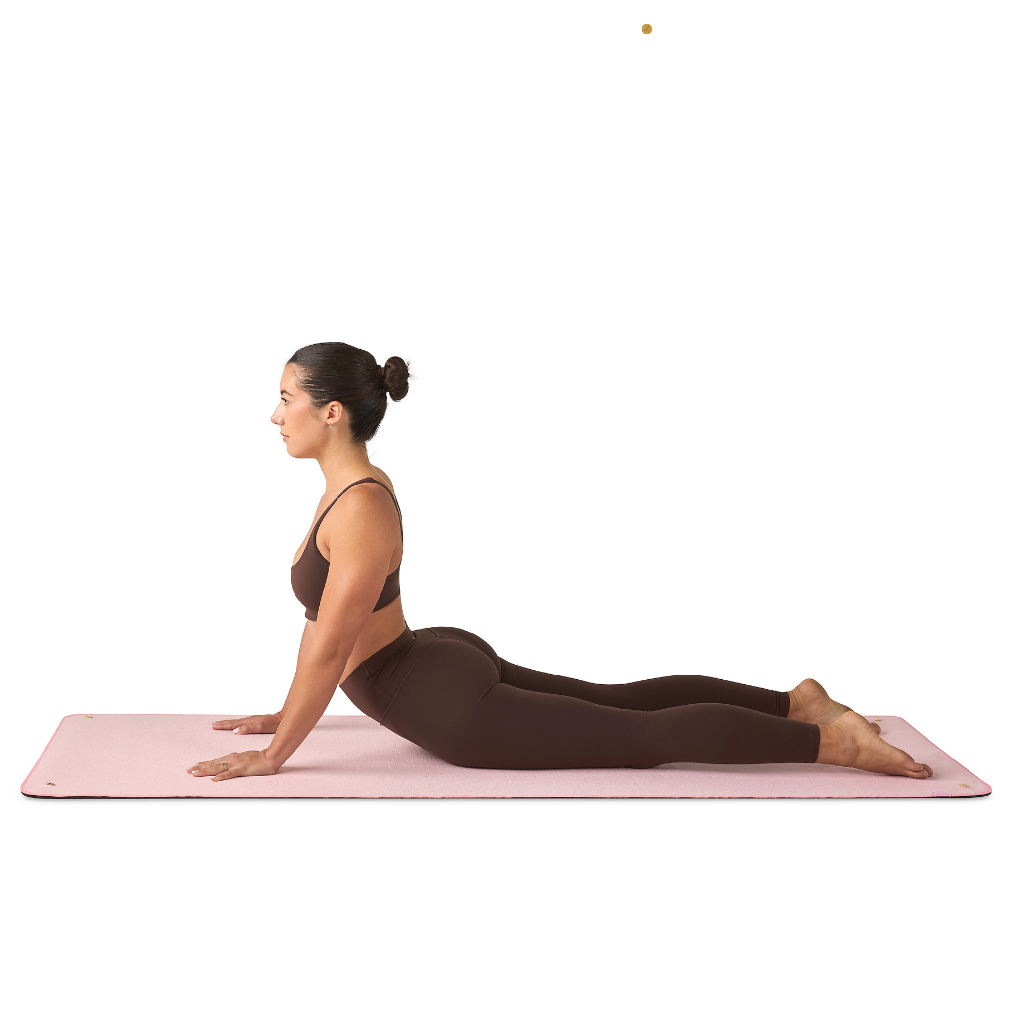 Woman performing a yoga pose on a pink mat towel with a white background