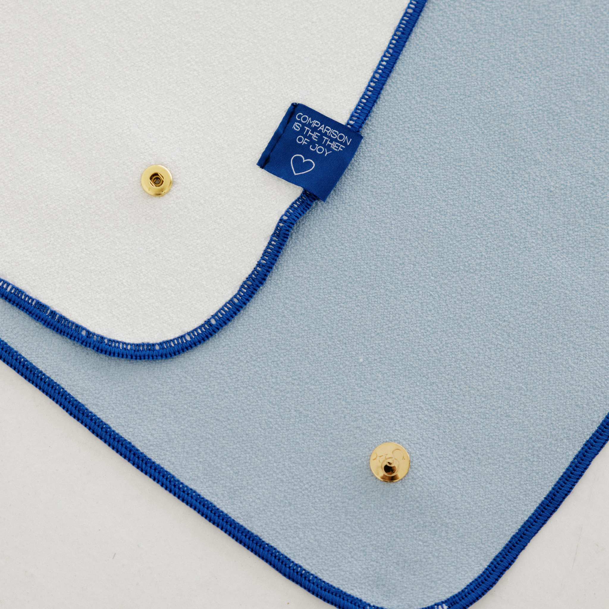 light blue yoga mat towel with gold snaps and "comparison is the thief of joy" label